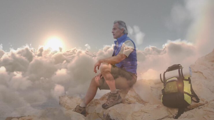 Uomo anziano caucasico felice che fa escursioni in montagna, con sovrapposizione di nuvole in rapido movimento.