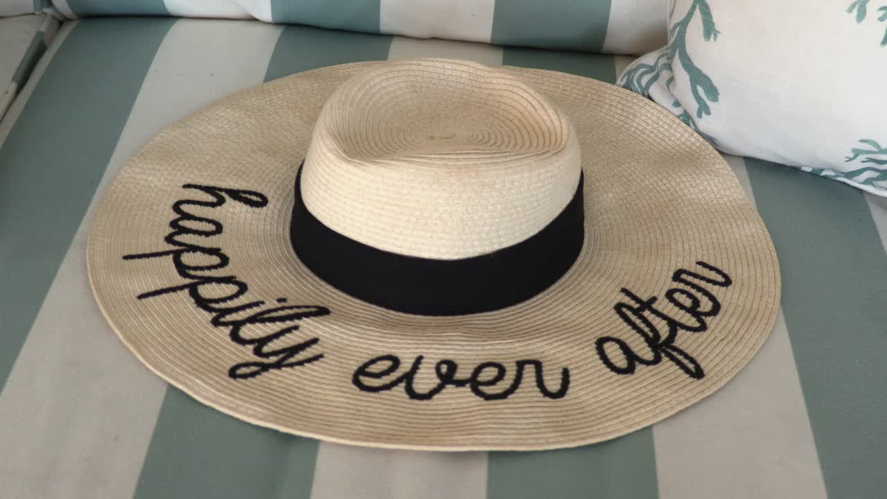 felizmente para siempre sombrero de paja recostado en un sofá a rayas en una casa de playa