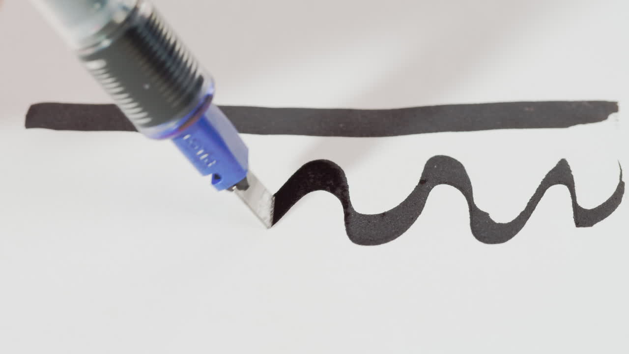 Primo piano di una penna calligrafica che traccia una linea ondulata
