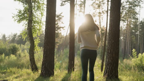 woman jogging on grass among trees at sunset. female runner enjoys cardio activity with stunning views of dense forest in evening. workout in nature alone