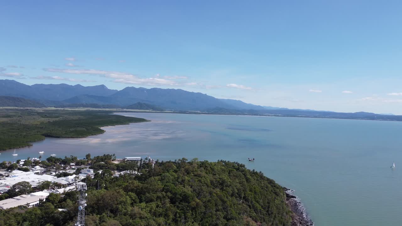 Vista aerea 4K di una splendida costa con una piccola cittadina costiera e una baia con montagne sullo sfondo in Australia