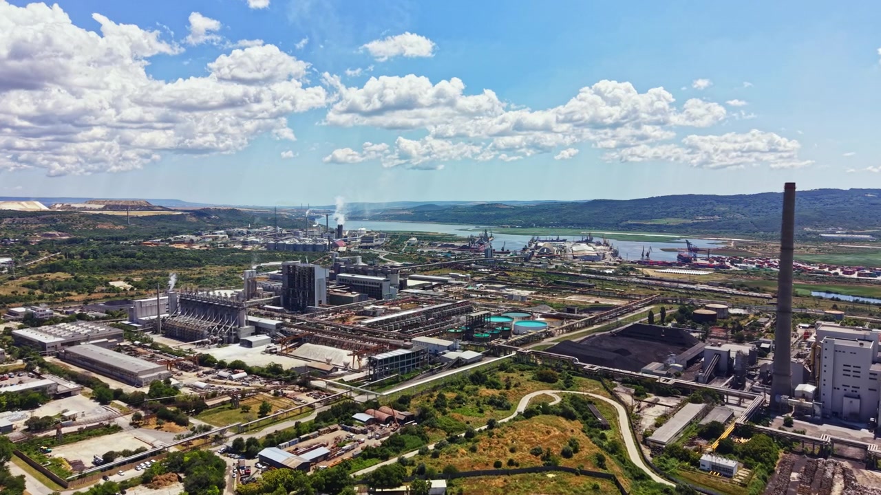 Vista de una zona industrial junto a un río con fábricas, maquinaria y edificios bajo un cielo azul durante el día