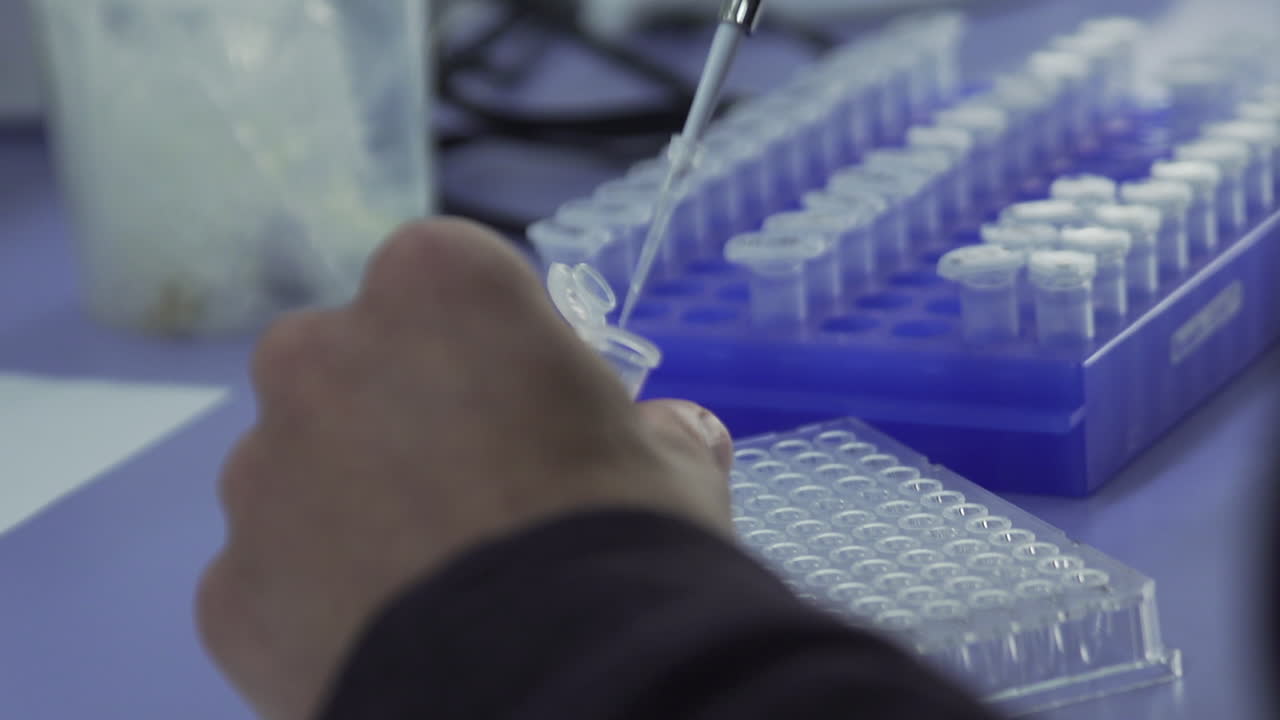 Lab Working Inserting Fluid into Reaction Tube, Over The Shoulder