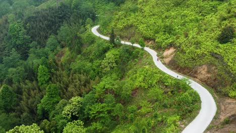 Lone-motorcycle-rider-travels-along-a-narrow-mountainous-road,-aerial