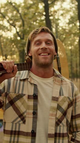 happy man with guitar in the woods