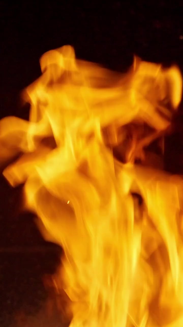 Primo piano di vivaci fiamme di fuoco arancioni e gialle che bruciano nel buio
