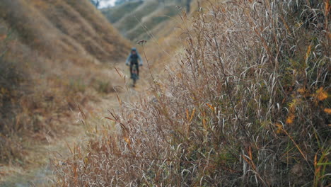 ciclista masculino montando una bicicleta de montaña en la colina por la carretera en medio del valle