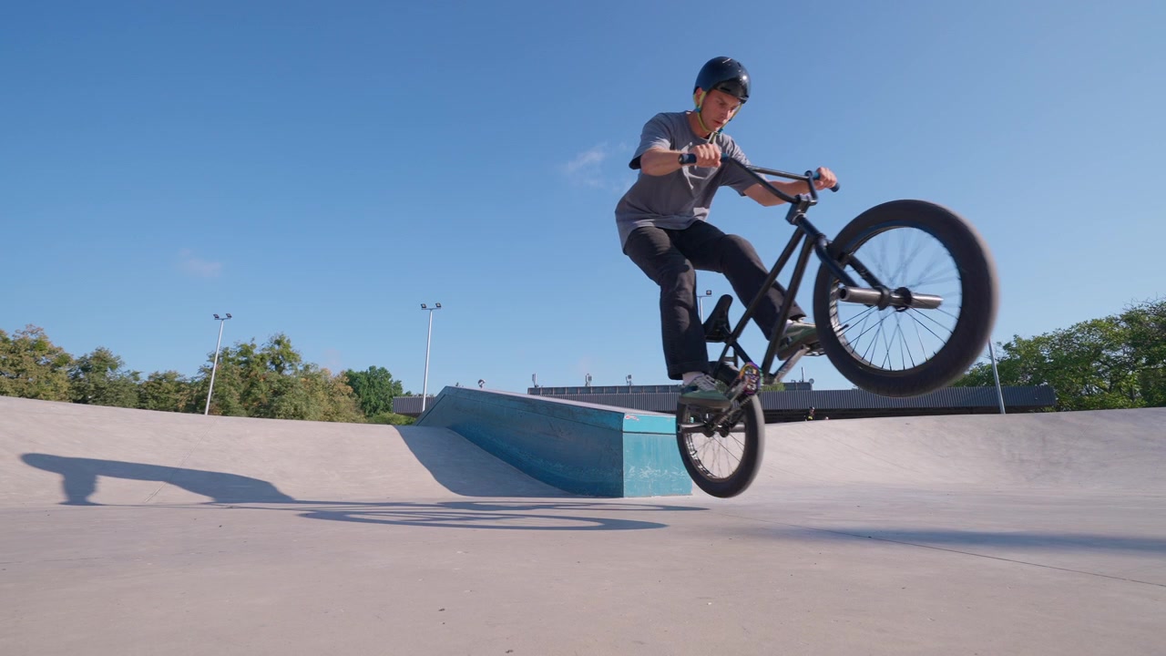 Ung BMX-rytter udfører et balancetrick på en rampe i en skatepark