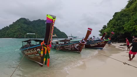 people pulling boats onto a sandy beach