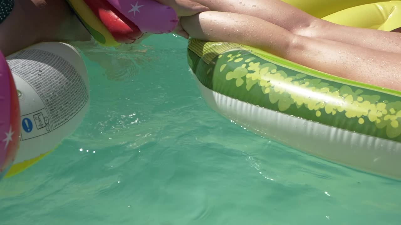 vista de cerca de las niñas jugando en la piscina con coloridos flotadores - cámara lenta