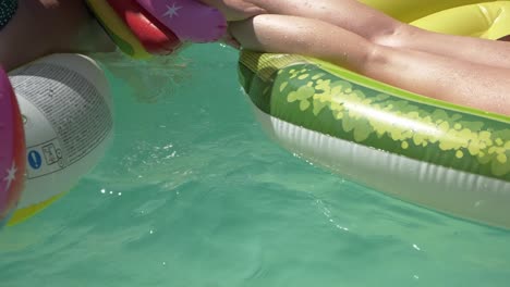 close up view of girls playing on pool with colorful floaties - slow motion