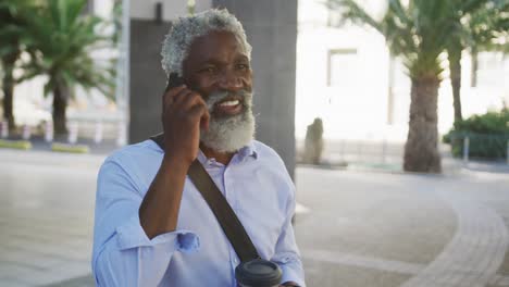 Afroamerikanischer-älterer-Mann,-Der-Im-Firmenpark-Auf-Dem-Smartphone-Spricht