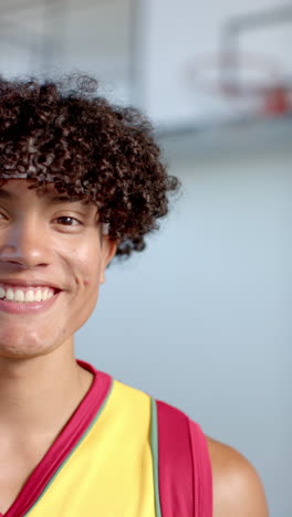 vertical video: smiling basketball player in jersey standing on court, ready for game