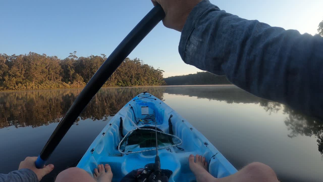 Una ripresa in soggettiva di un uomo che pagaia in kayak su un lago nebbioso al mattino presto in Australia