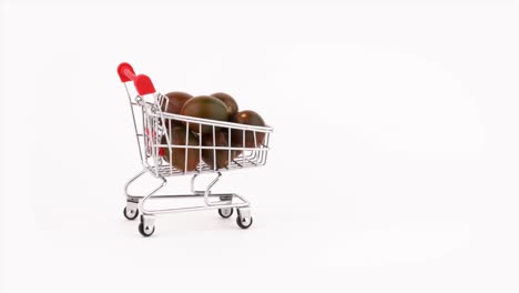 el carrito del supermercado se mueve lleno de tomates de uva negra. aislado en el fondo blanco. primer plano. macro.