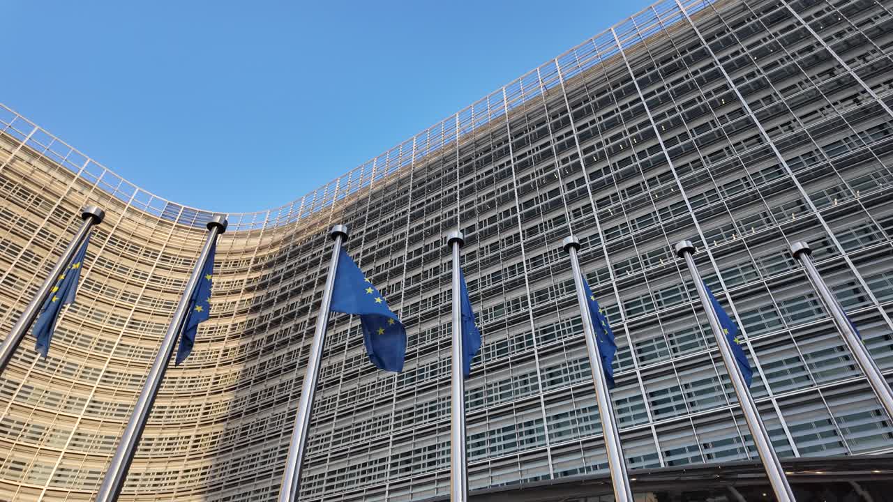 Camera pans up from entrance to EU flags at Commission building