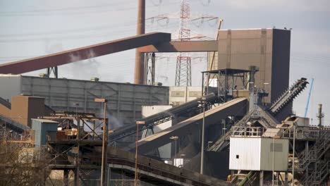 Industrial-complex-with-conveyors-and-smokestacks,-day,-symbolizing-heavy-industry-and-manufacturing