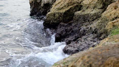 calm waves hiting rocks on a gloomy day in slow motion