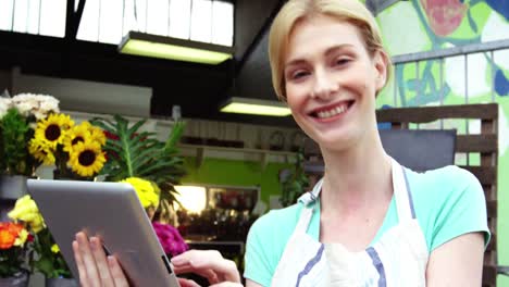 florista sonriente usando una tableta digital en la floristería
