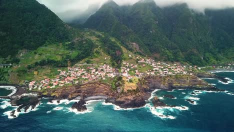 breathtaking aerial view of seixal, a picturesque coastal village in northern madeira island, highlighting natural lava pools and powerful atlantic waves crashing against rugged cliffs