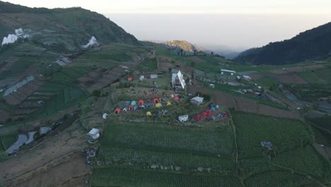 Vista-Aérea-Sobre-La-Colina-Skoter-Con-El-Campamento-Cerca-De-La-Aldea-De-Dieng-Kulon,-Distrito-De-Batur-En-Java-Central