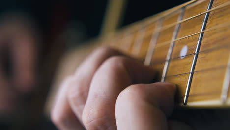 person plays guitar striking chord and moving little finger