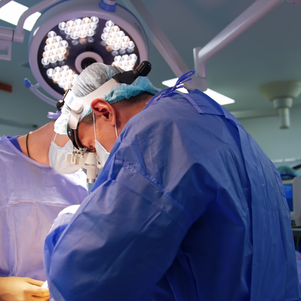 Neurochirurgo con occhiali tecnologici che parla alla fotocamera. Il dottore si rivolge a un paziente e utilizza strumenti e apparecchiature.