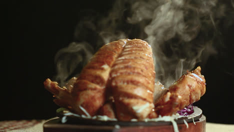 close up of roasted chicken bbq on round table with smoke black background