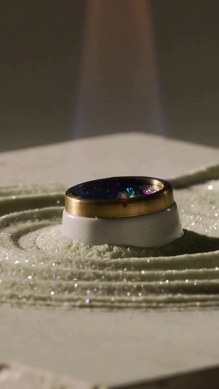 Video verticale: Torcia che applica la fiamma a un anello d'oro su un piedistallo, cambiando il colore della resina, con polvere scintillante.