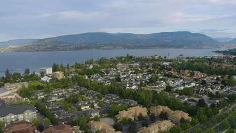 ángulo-Aéreo-Retrocediendo-Para-Revelar-Casas,-Montañas-Y-El-Lago-Okanagan-En-Kelowna,-Columbia-Británica