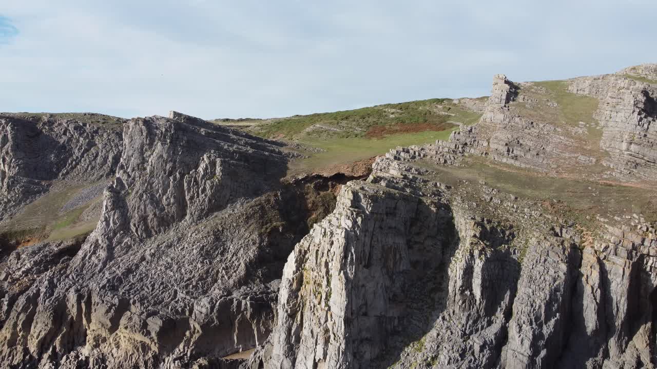 gower 반도 영국의 mewslade 만에 잔디와 다양한 암석 풍경이 있는 극적인 해안 절벽 - 공중 드론 샷 4k