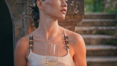 glamorous girl holding wineglass enjoying evening sunlight in old castle closeup