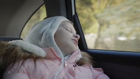 the child sleeps while driving in the back seat of a car.