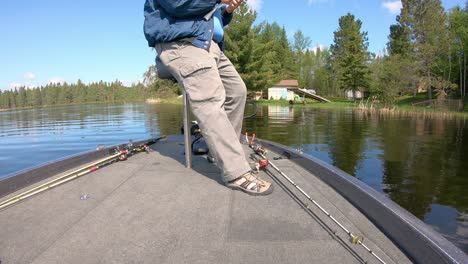 man fishing with an open face reel and artificial lure while leaning on a butt seat in the front of a bass boat