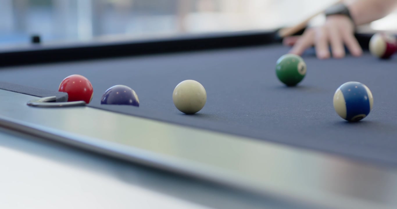 Joueur reculant sa queue, frappant la bille blanche, envoyant les billes vers la poche gauche de la table pour marquer.