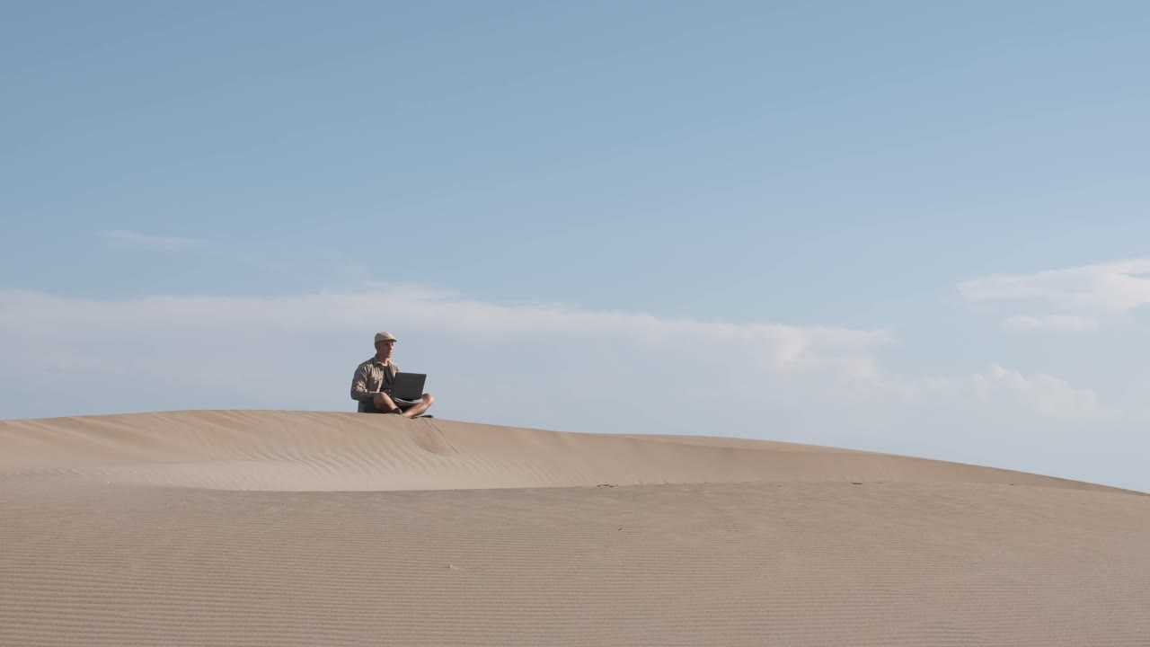 Man works on laptop in the desert. Digital nomad and remote worker concept