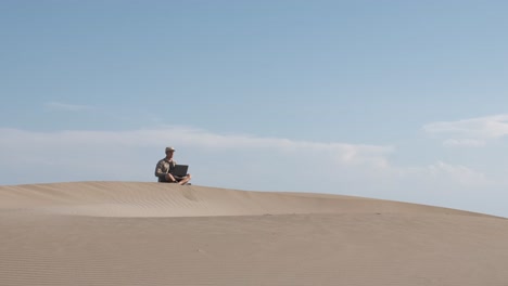 man works on laptop in the desert. digital nomad and remote worker concept