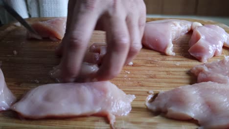 Cook-Slicing-Fresh-Chicken-Meat-Into-Strips-Using-Sharp-Knife-In-Wooden-Board---high-angle,-close-up