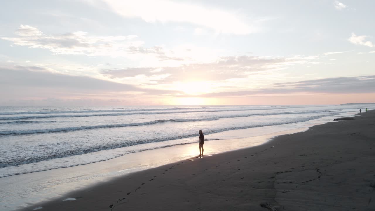 일몰 때 코스타리카 중앙태평양 지역의 그림 같은 열대 해변을 따라 걷고 있는 젊은 여성
