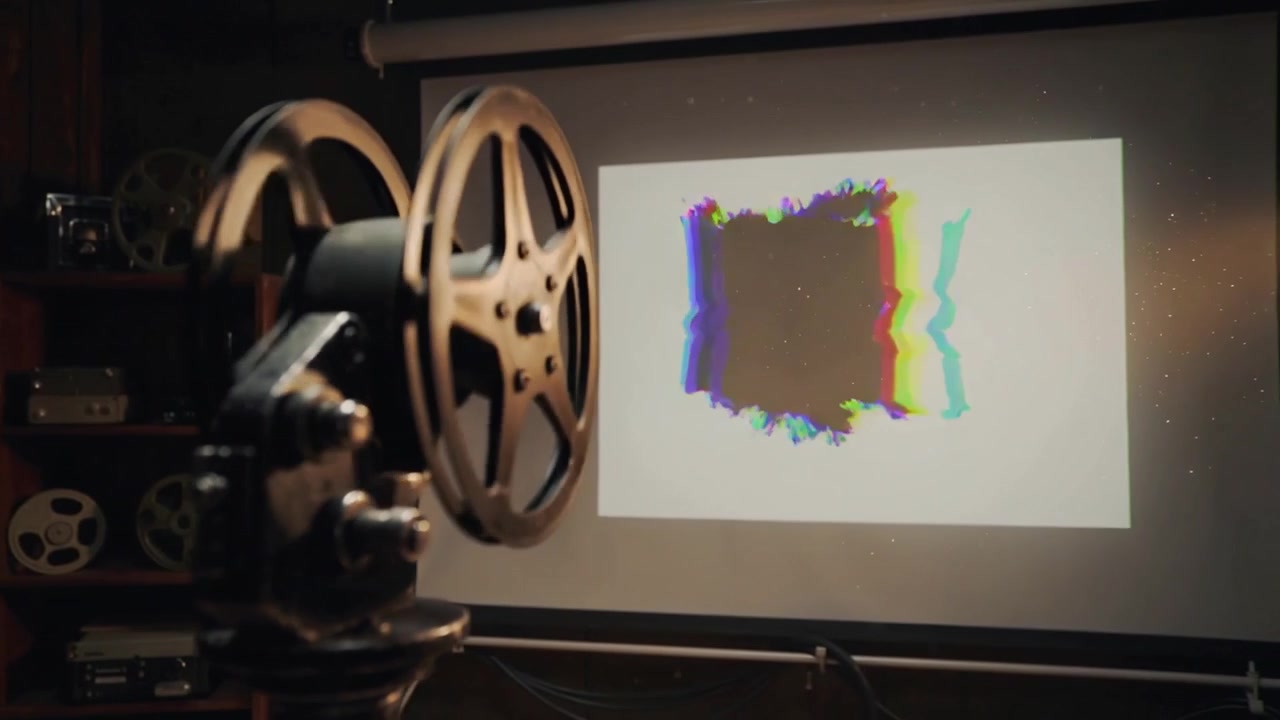 Proiettore cinematografico d'epoca in funzione, con le due bobine che girano e proiettano un quadrato con glitch sullo schermo.