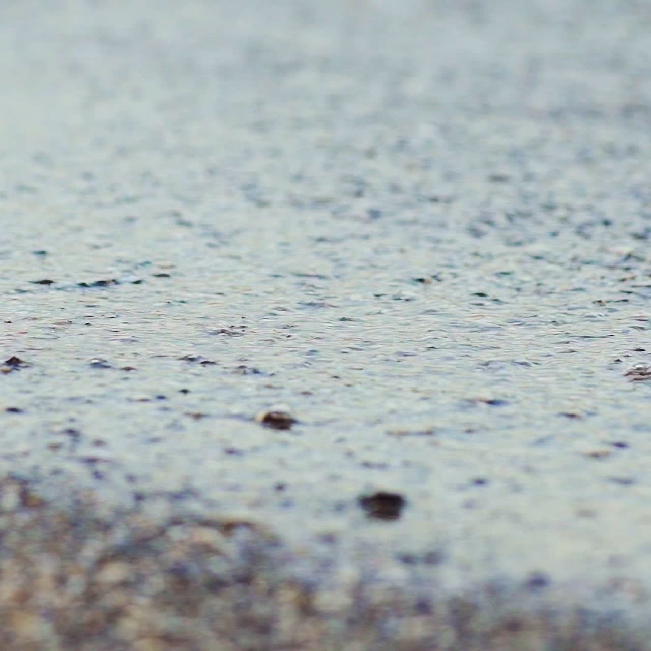 Flowing sea water on the pebble beach in the evening. The edge of the ocean with calm waves on the pebble background. Close-up.