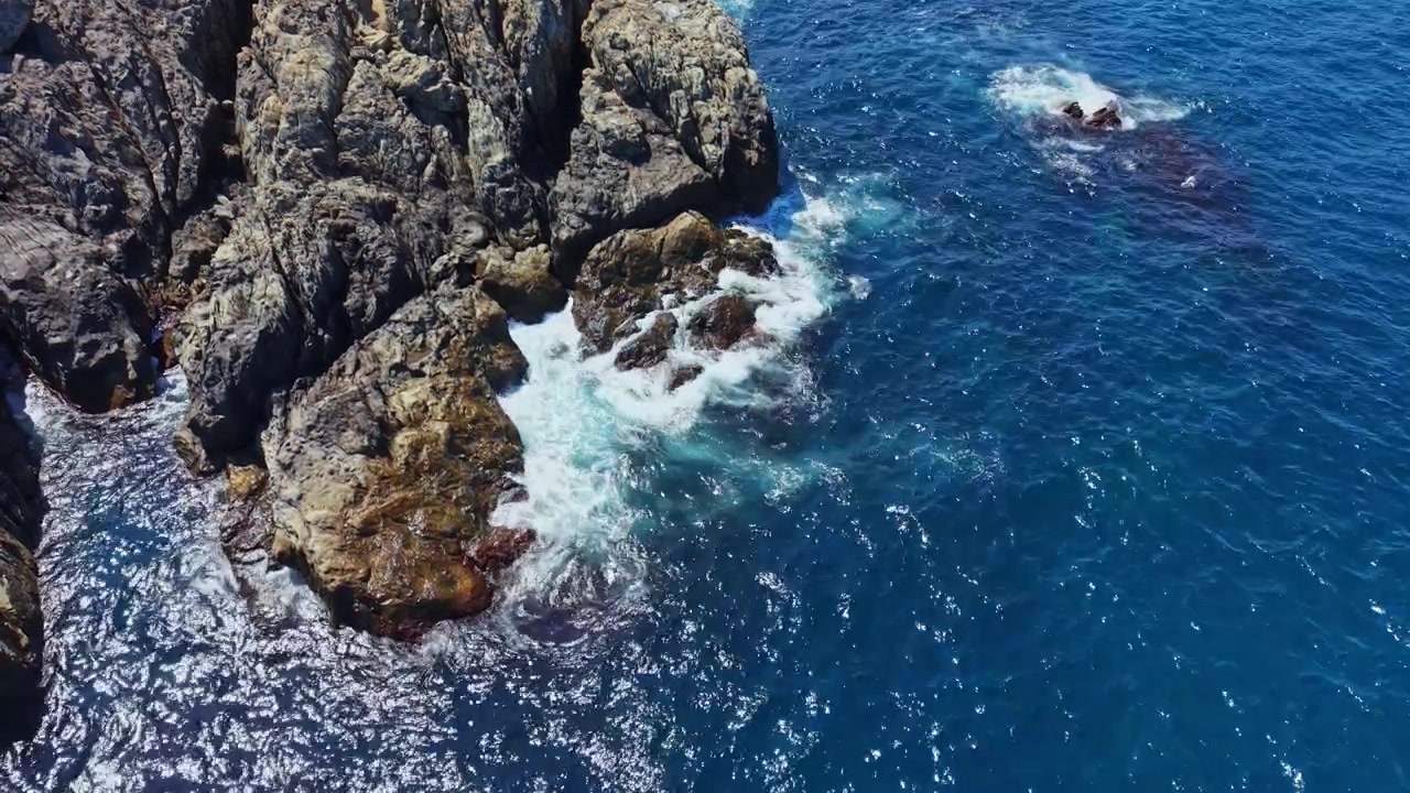 Costa rocciosa incontra le onde dell'oceano in una località soleggiata.