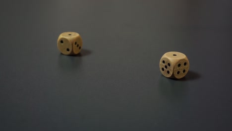 Dice-Roll---Two-Wooden-Dice-Rolling-On-Black-Table-Getting-Double-One