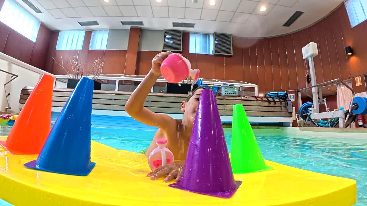 Boy Playing in Swimming Pool with Cones