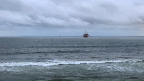 4k-60p,-Plataforma-Petrolera-En-Alta-Mar-Al-Atardecer-Con-Un-Cielo-Nublado-Y-Olas-Rodando