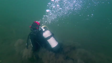 scuba diver swimming underwater with bubbles. close up