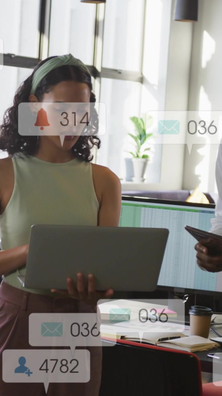 Vertical video: Woman holding laptop, peer showing phone, causing likes and checking media for ads