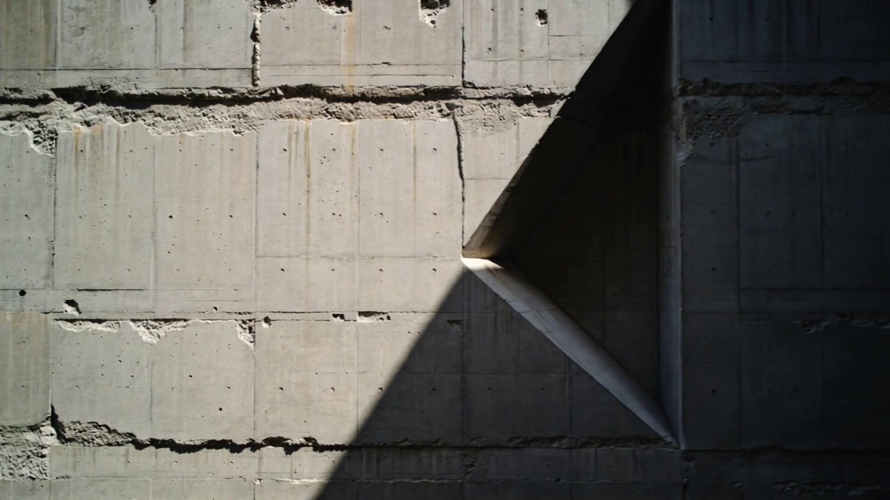 Shifting sunlight revealing triangular recess on exterior wall, exposing formwork lines, copy space