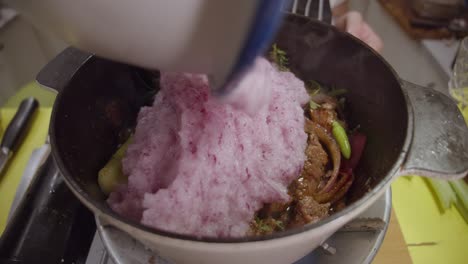 adding alla genovese sauce into a deep cooking pot with beef shank, onion slices, celery and spices