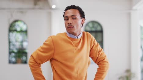 biracial male dancer with earrings dancing alone in dance studio, slow motion
